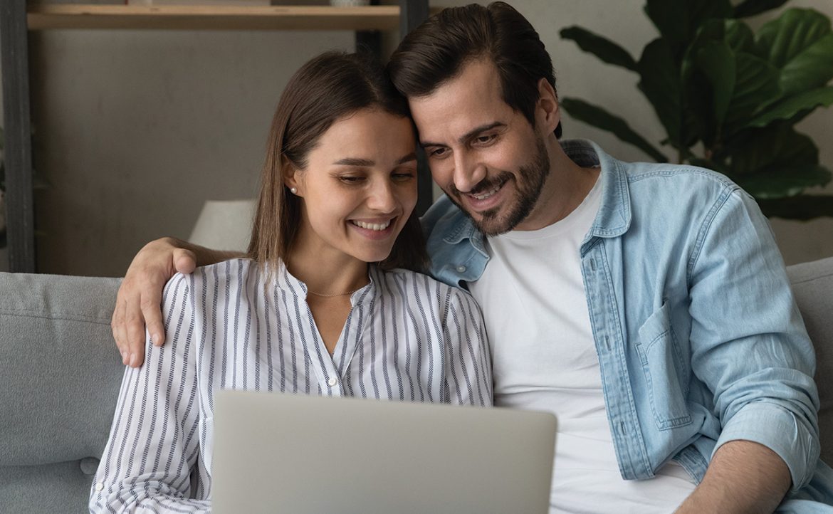 pareja-sentada-sonriendo-delante-de-una-computadora